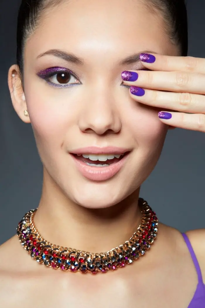 maquillage pour yeux marron avec fards à paupières violet et crayon bleu, manucure violet avec décoration en paillettes