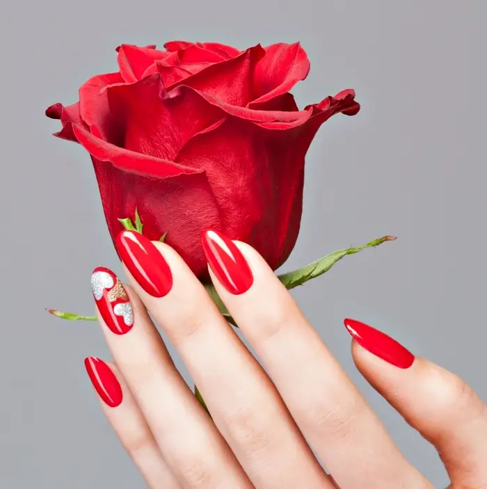 idée pour la manucure de Saint Valentin version ongles longs, vernis gel de nuance rouge avec décoration coeur argent et or